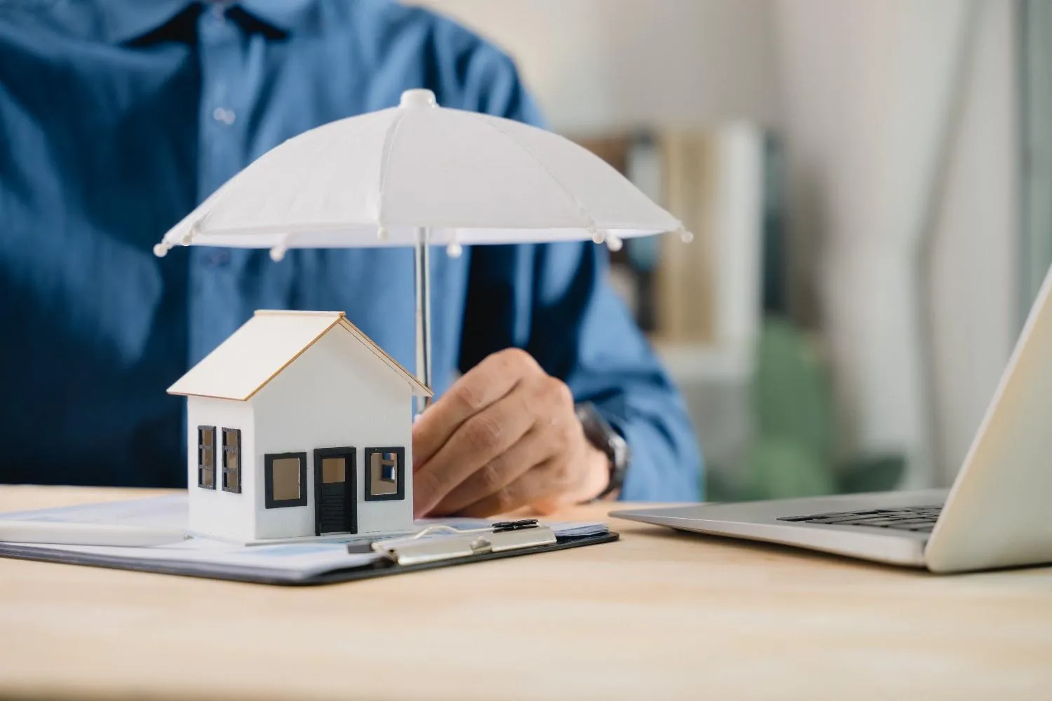 Model house sheltered under a small white umbrella